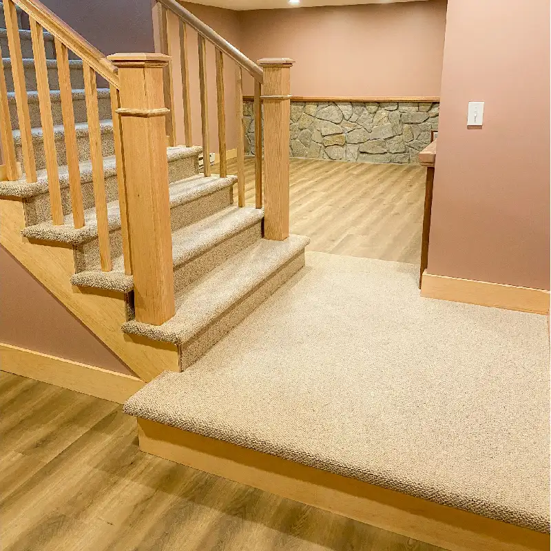 Carpeted staircase with wooden railing and beige carpet extending to hardwood floor