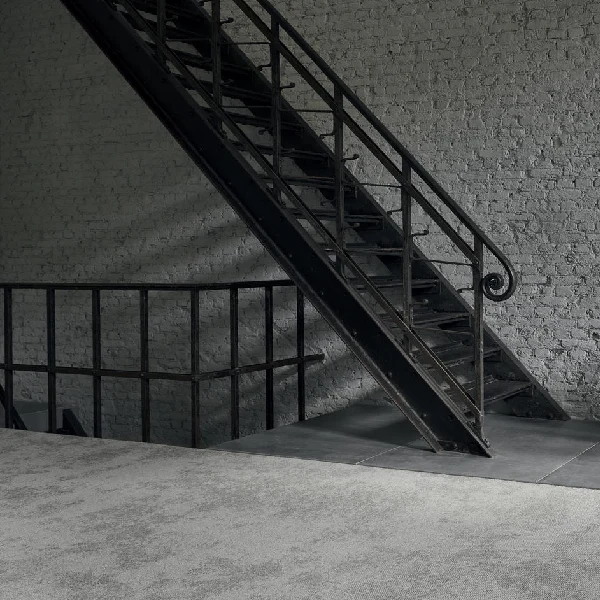 Light gray industrial carpet at the base of metal stairs.
