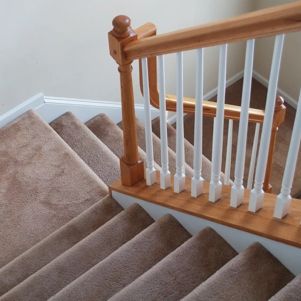 light brown carpet installed on a wooden staircase with white spindles